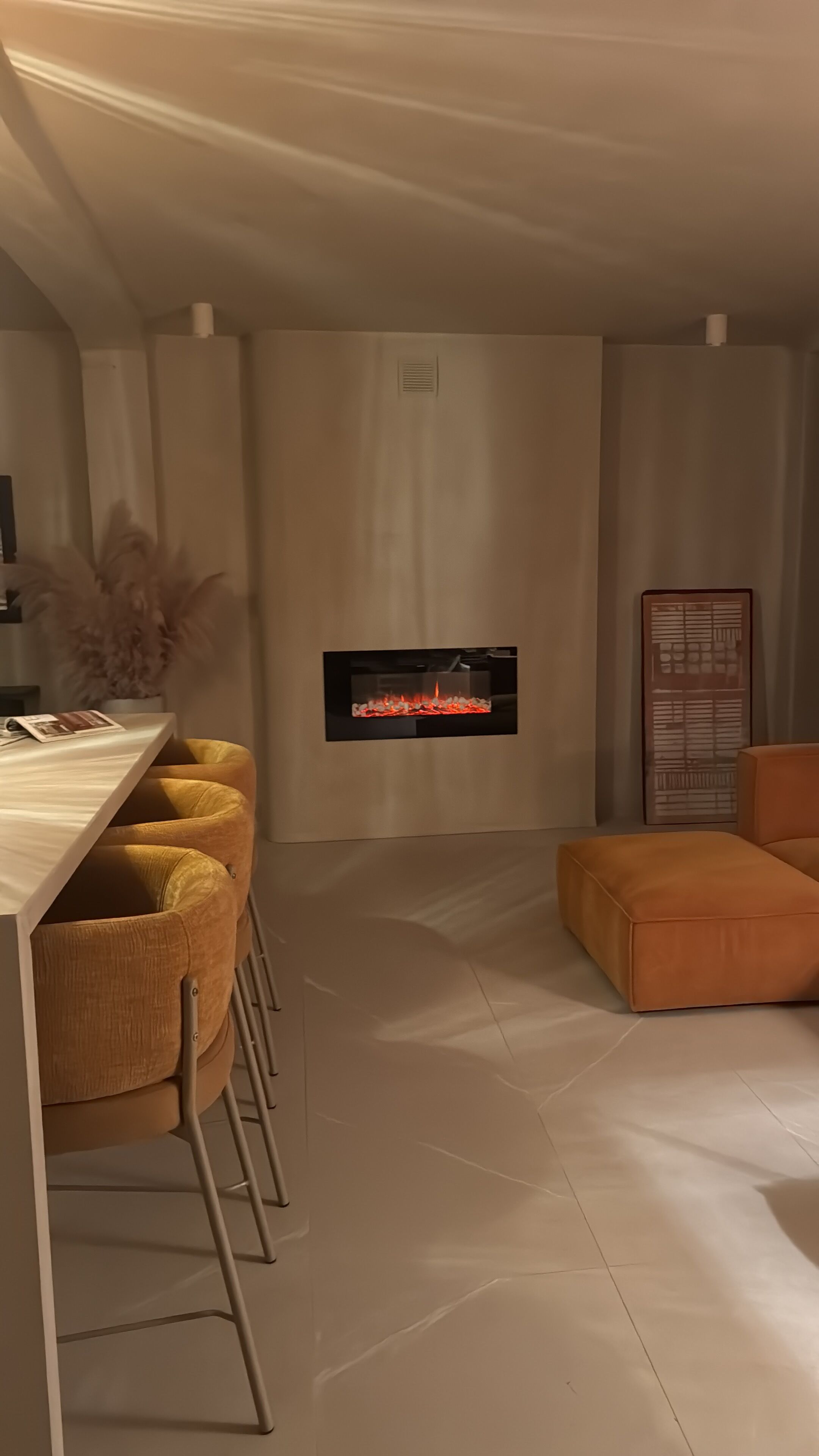 A modern living room with a fireplace, a bar area with stools, and a sofa.
