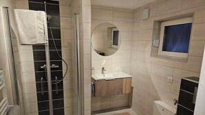 Une salle de bain moderne avec une douche à parois de verre, un meuble-lavabo avec un miroir et des toilettes.
