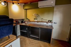 A compact kitchen with a wooden countertop, built-in cabinets, and a white door.