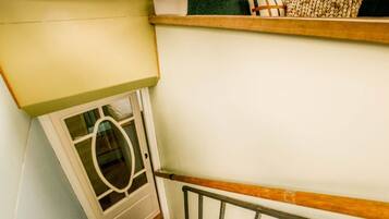 A staircase with a wooden handrail, a white door with a glass panel, and a shelf with decorative items.