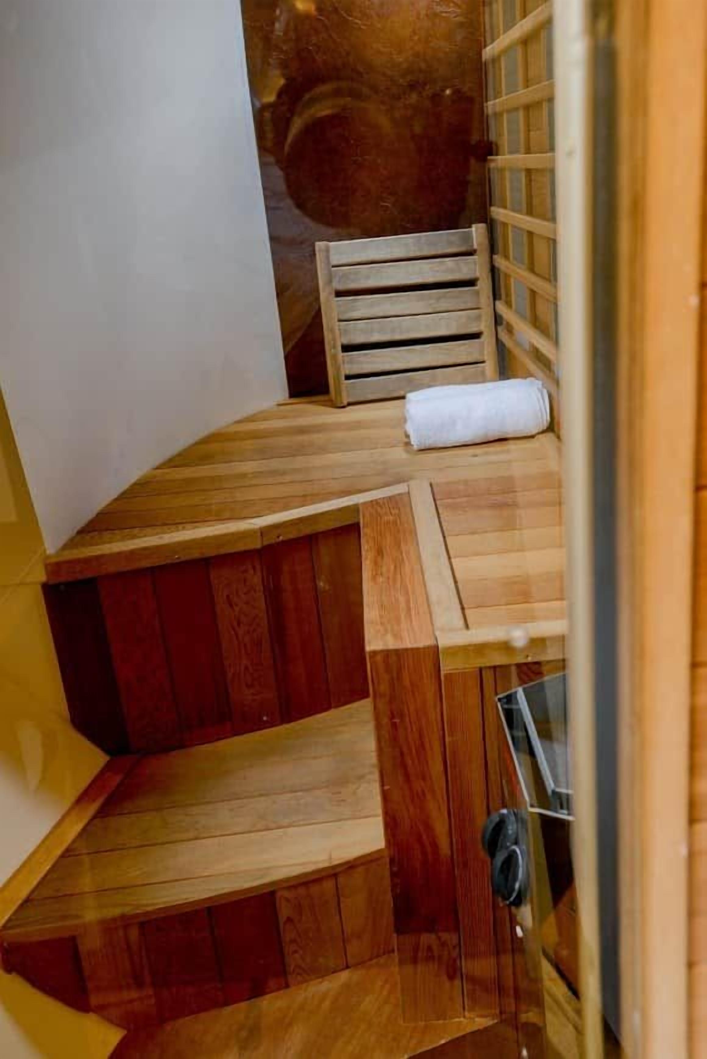 A wooden bench with a towel, a wooden ladder, and a metal door.