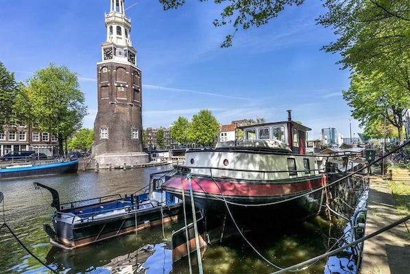 A canal with boats, a historic tower, and buildings along the water.