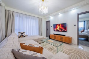 Ein modernes Wohnzimmer mit Sofa, Glastisch, Holz-TV-Möbel und einem Gemälde von Feuer.