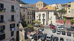 A multi-story building with balconies, a parking area, and a mountain in the background. - BROTHER'S HOUSE APARTMENT (Salerno)