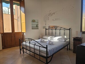 Une chambre à coucher avec un lit, une fenêtre, un élément de décoration murale et une table de chevet.
