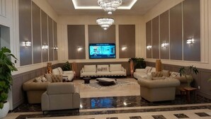 Un vestíbulo espacioso con un amplio conjunto de sofás, una pantalla de televisión y un candelabro.