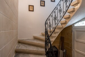 A staircase with a wrought iron railing, beige steps, and a white door at the bottom. - Regina Suite: 2-bed apartment in Valletta (Valletta)
