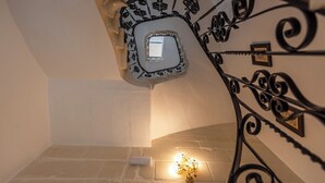 A staircase with a decorative metal railing and a small light fixture at the bottom. - Regina Suite: 2-bed, 2 en-suite apartment in Valletta with AC and comfort (Valletta)