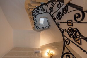 Eine Treppe mit dekorativer Metallreling und einer kleinen Leuchte am Fuß.