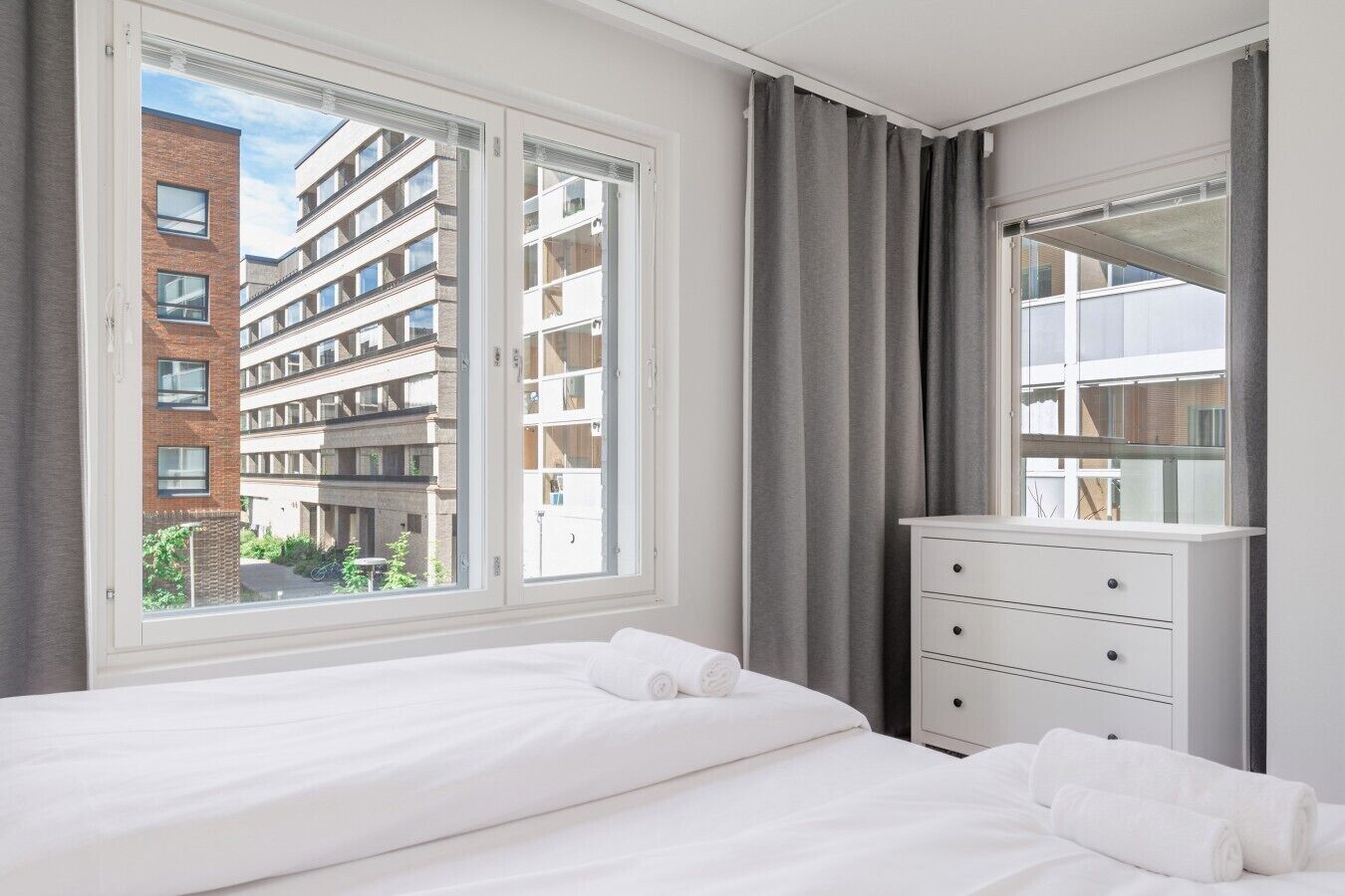Een hotelkamer met een groot bed, een dressoir en uitzicht op een gebouw.