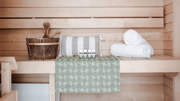 A wooden sauna with a bench, a basket, a towel, and a patterned cloth. - Large 3BR • Sauna • Free Parking • Walk to ferries (Helsinki)