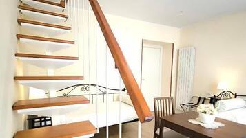 Eine Treppe führt zu einem Schlafzimmer mit einem Bett, einem Esstisch mit Stühlen und einer Lampe.