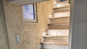 A staircase with wooden steps and stone accents, leading to a landing with a small window. - 1,001 Wonders (Fénay)