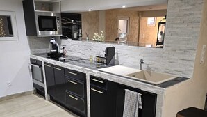 A modern kitchen with a central island, built-in appliances, and a stone backsplash. - 1,001 Wonders (Fénay)