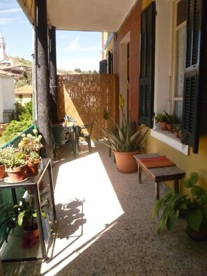 A balcony with potted plants, a table, and chairs. - Casa dell'Arte ArtGarage (Imperia)