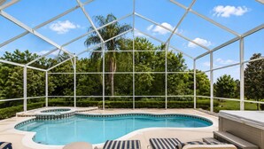 Une piscine couverte avec un jacuzzi, des chaises longues et une vue sur un jardin aménagé.