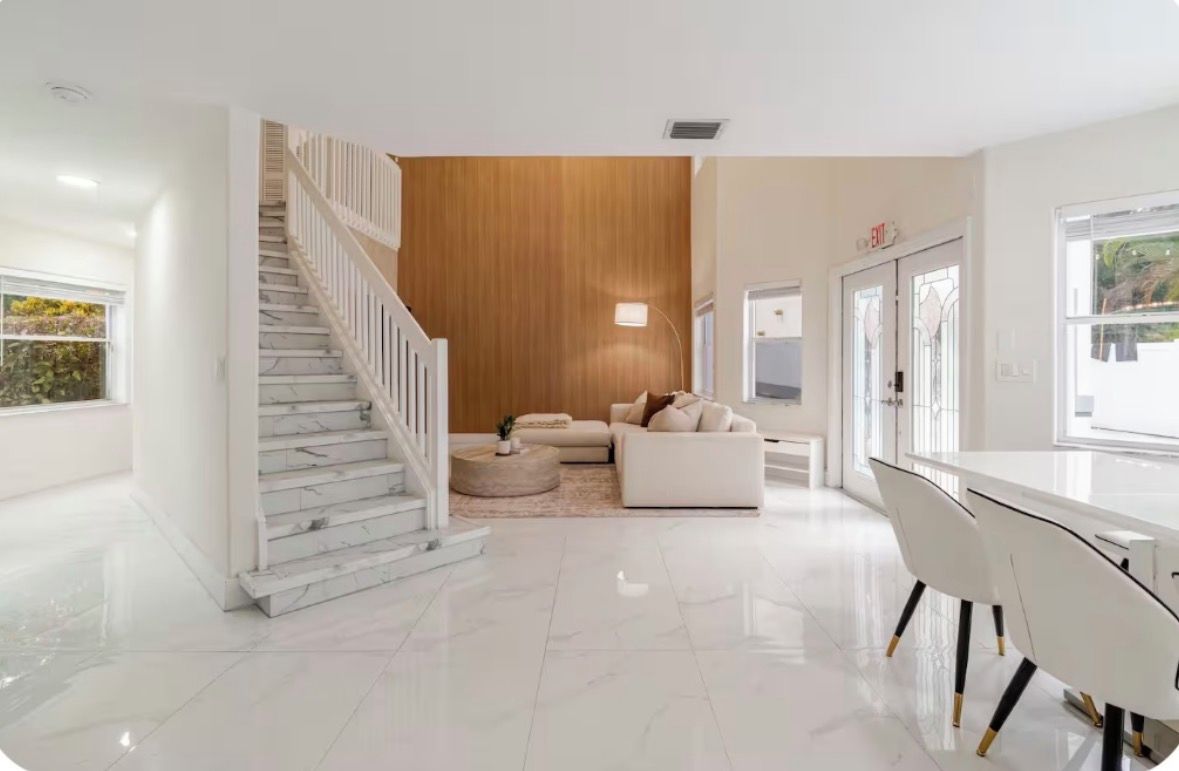 Een modern interieur met een trap, een witte bank en een eettafel.