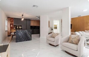 A modern living room with a marble island, a sofa, and a dining area with wooden furniture.