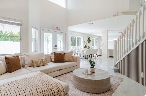 A spacious living area with a sofa, coffee table, and a staircase.