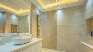 Un bagno moderno con un grande specchio, un lavandino bianco e una zona doccia.
