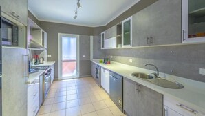 Una cucina moderna dotata di forno a microonde, piano cottura, lavello e lavastoviglie.