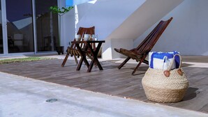 An outdoor seating area with a table and chairs, a woven basket, and a building with large windows and a white exterior. - Casa Akna Chicxulub by Casago (Chicxulub)