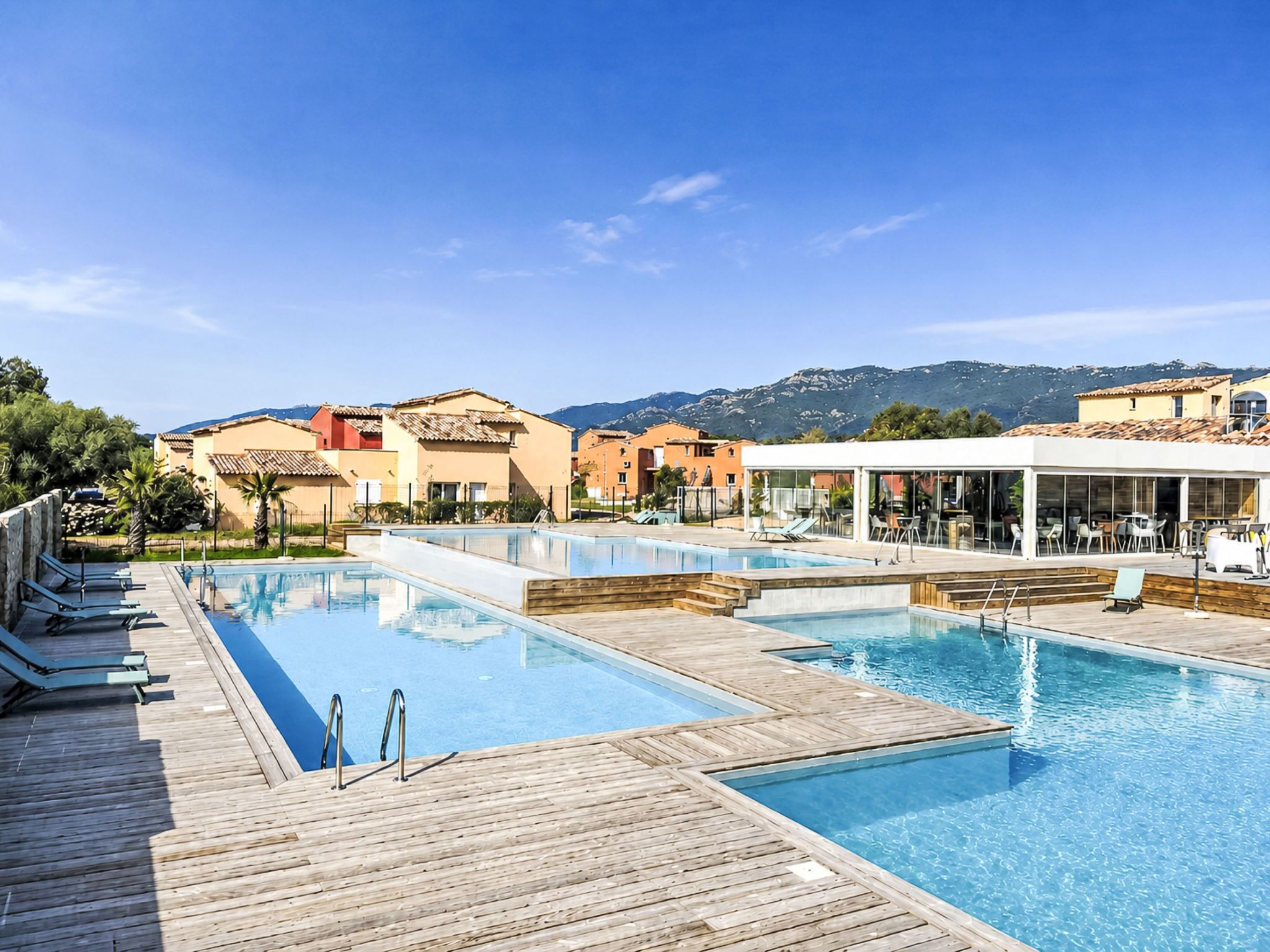 Ein Resort mit mehreren Schwimmbecken, Holzdeck-Terrassen und Gebäuden im mediterranen Stil.