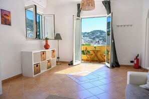 Una habitación con un ventanal grande, una consola blanca, un sofá y vistas a una colina.
