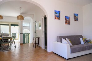 Una sala de estar con sofá, mesa de comedor, sillas y una zona de cocina.