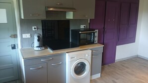 A compact kitchen with a microwave, coffee maker, and washing machine. - Atchoum Vacation Rental (Hostun)
