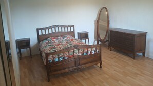 A bedroom with a wooden bed, a dresser, a mirror, and two nightstands. - Atchoum Vacation Rental (Hostun)