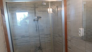 A modern bathroom with a glass-enclosed shower, a white sink, and a wooden-framed mirror. - Atchoum Vacation Rental (Hostun)