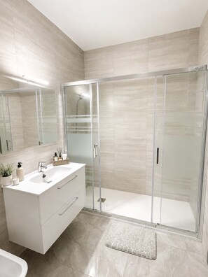 Une salle de bain moderne avec une douche à parois de verre, un meuble-lavabo blanc et un grand miroir.
