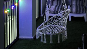 A hanging chair, a white sofa, and a balcony with a railing.