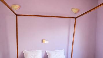 Ein Zimmer mit Holzbalkendecke, einem Bett mit weißer Bettwäsche und einer kleinen Blume auf dem Bett.