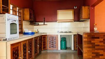 Una cocina con armarios de madera, un horno blanco, una estufa a gas y un cilindro de gas verde.