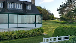 A house with a large window, a white fence, and a well-maintained lawn. - Superb Sea Views Private Beach Access (Saint-Pabu)