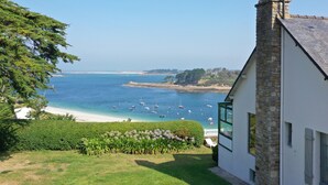 A coastal view with a stone building, a grassy area, and boats on the water. - Superb Sea Views Private Beach Access (Saint-Pabu)