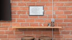 A brick wall with a framed map of Lubbock, Texas, a shelf with a radio, and two stools. - Tech Terrace Retreat - TTU, J&B Coffee, Brewery (Lubbock)