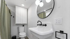 A bathroom with a toilet, sink, mirror, and shower curtain. - Tech Terrace Retreat - TTU, J&B Coffee, Brewery (Lubbock)