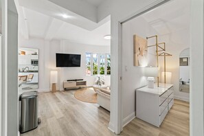 Ein modernes Wohnzimmer mit Flachbildfernseher, einer Couch, einem Couchtisch und einer Lampe.