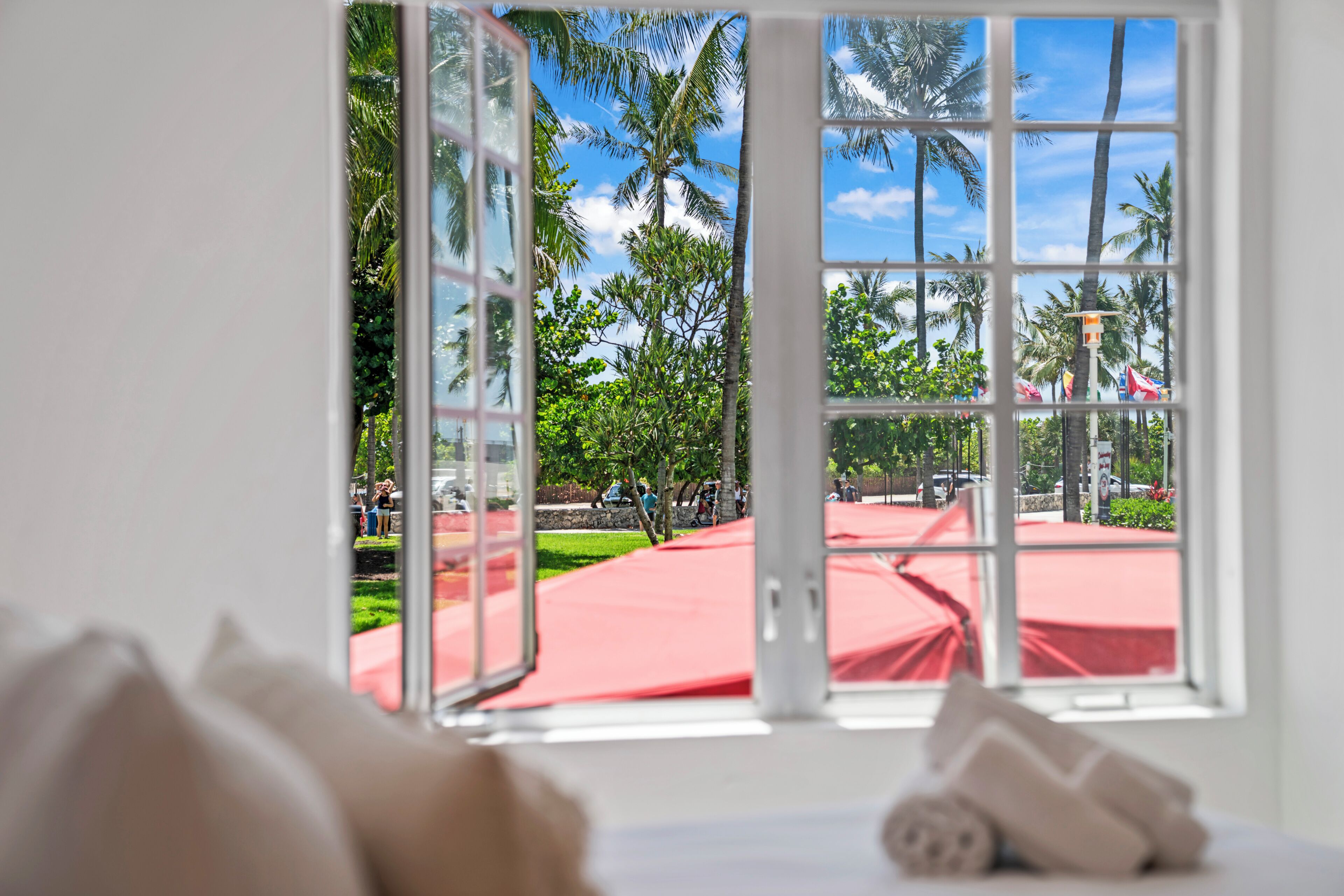 A room with a large window overlooking a red-roofed outdoor area with palm trees and a clear sky.