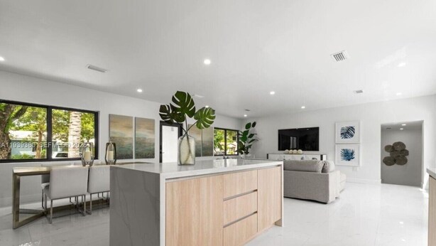 Een moderne keuken met een centraal eiland, een eethoek met stoelen, een bank en kunstwerken aan de wanden.