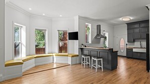 A kitchen with a curved bench, a bar area, and a large window. - La Casa Vallejo - Historic Highlands home sleeps 10, walk to dining & bars (Denver)