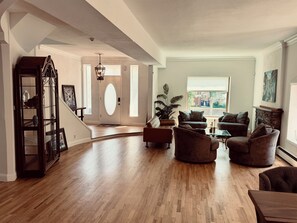 A spacious living room with hardwood flooring, a staircase, and a large window providing natural light. - La Casa Vallejo - Historic Highlands home sleeps 10, walk to dining & bars (Denver)
