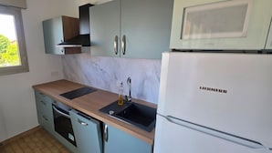 Une cuisine compacte équipée d’un four encastré, d’un évier et d’un réfrigérateur Liebherr.
