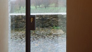 Ein Zimmer mit großem Fenster, einer Steinwand und einer Tür mit Schloss.