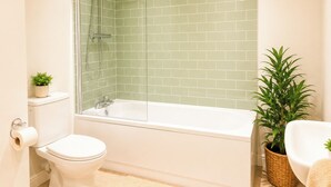 Een badkamer met een douche, toilet en bad.