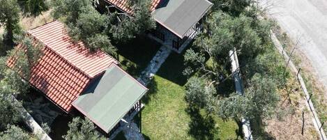 An aerial view of a property with two buildings, a paved driveway, and surrounding vegetation.