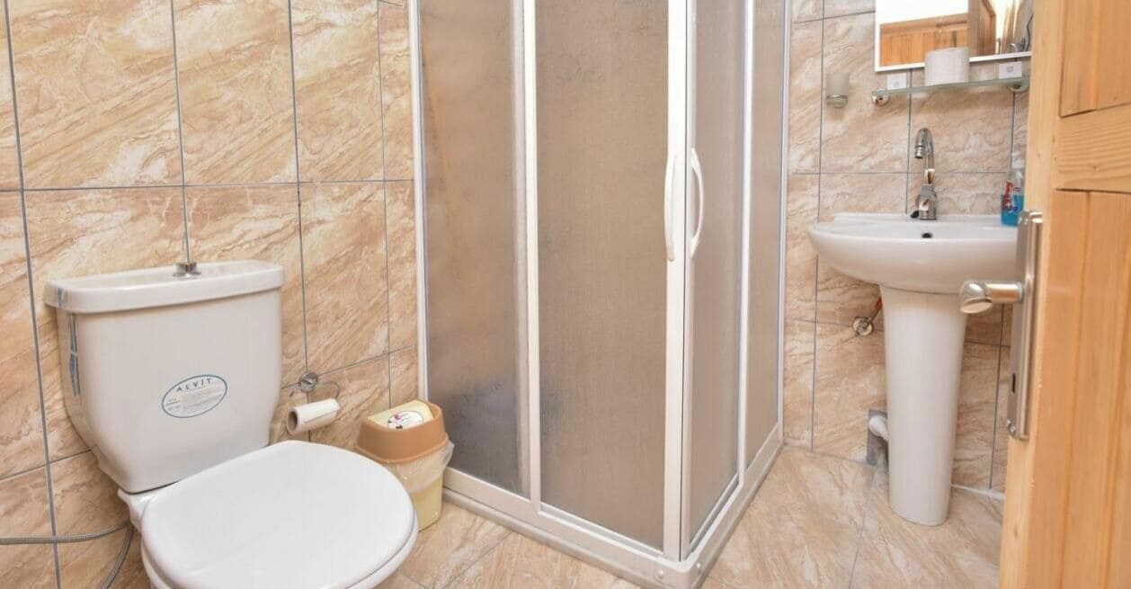Et badeværelse med toilet, bruser og håndvask.